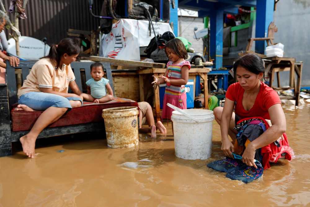 A woman washes clothing in a flooded street. A woman washes clothing in a flooded street.